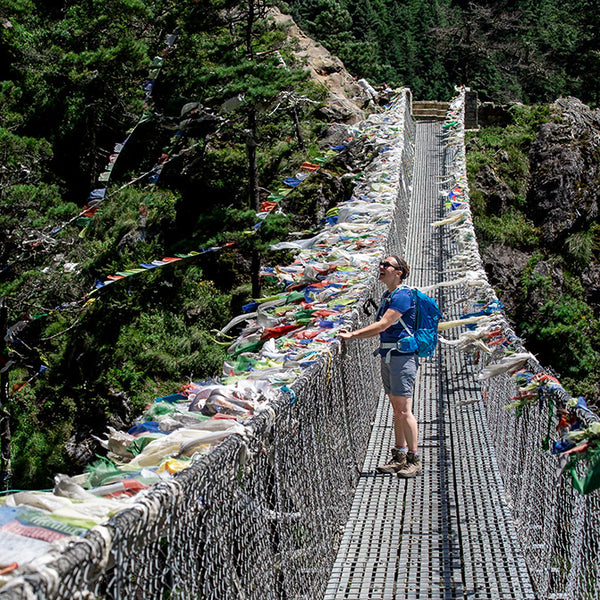Boundaway Founder hiking on a hanging bridge with prayer flags